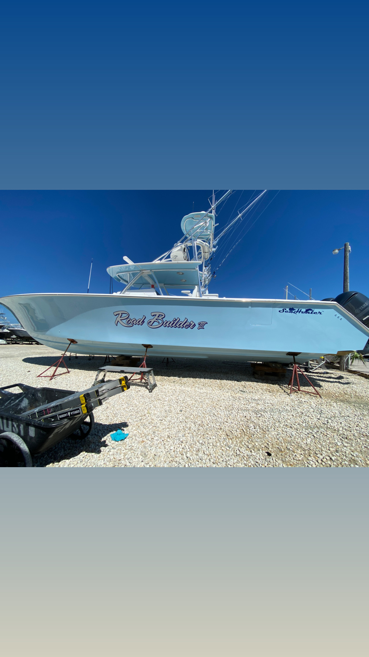 A boat is parked in a gravel lot.