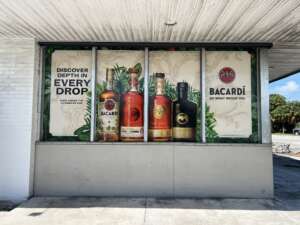 A storefront display featuring Bacardí rum bottles and the slogan "Discover Depth in Every Drop" with "Do What Moves You" at the bottom. The background has tropical leaves and a Caribbean-themed vibe.