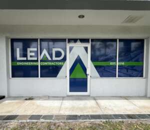 Front exterior of an office with the company name "LEAD Engineering Contractors" on the window. The design includes blue, green, and white colors, with "EST. 2016" on the right side.